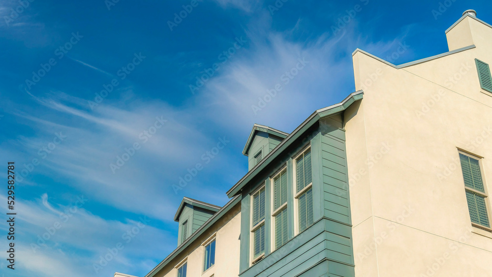 Panorama Whispy white clouds Low angle view of a residential building with beige and gray sid