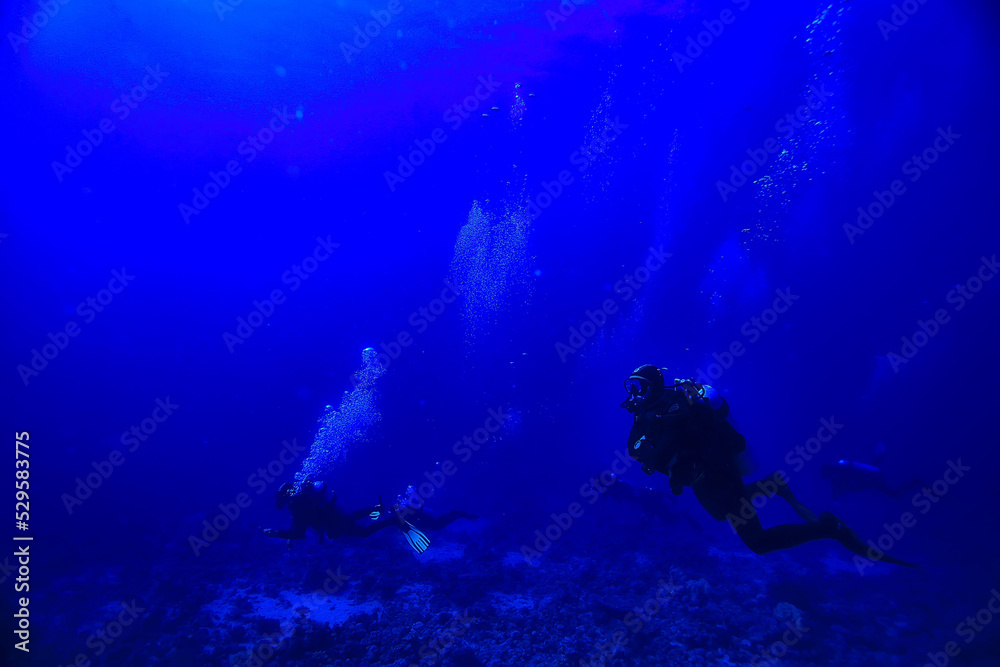 Obraz premium divers underwater at depth in the blue sea background