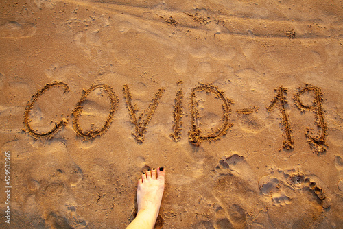 The inscription covid 19 on the sand on the beach in close-up. Restrictions on summer holidays due to the incidence of pneumonia and colds. Quarantine in hot countries. Vaccination for travel.