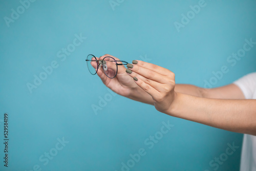 Female hand with stylish glasses on colorful background
