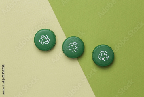 Plastic bottle caps with circular recycling symbol on green background. Round recycle concept