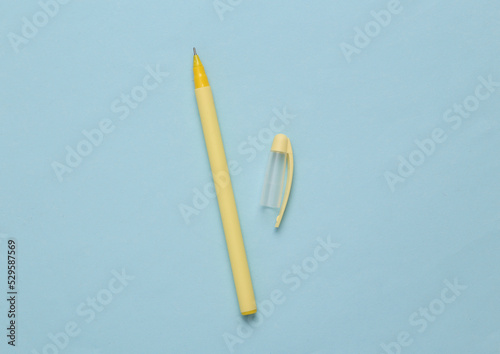 Yellow pen with a cap on blue background. Minimal concept