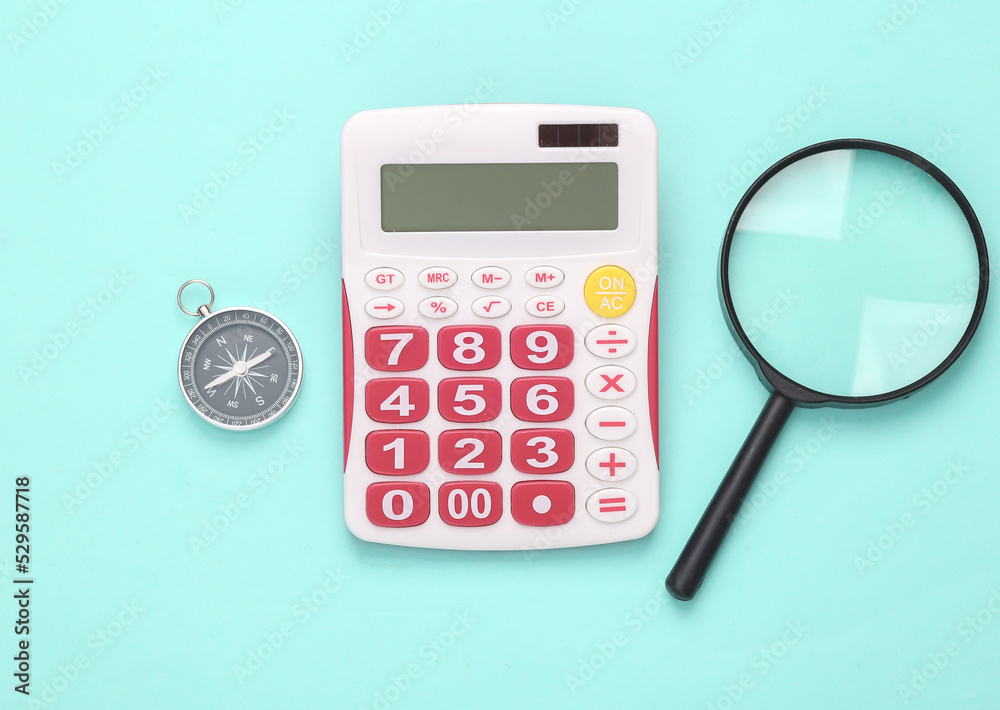 Calculator with a magnifying glass and compass on blue pastel background. Business concept. Top view Calculator with a magnifying glass and compass on blue pastel background. Business concept. Top view