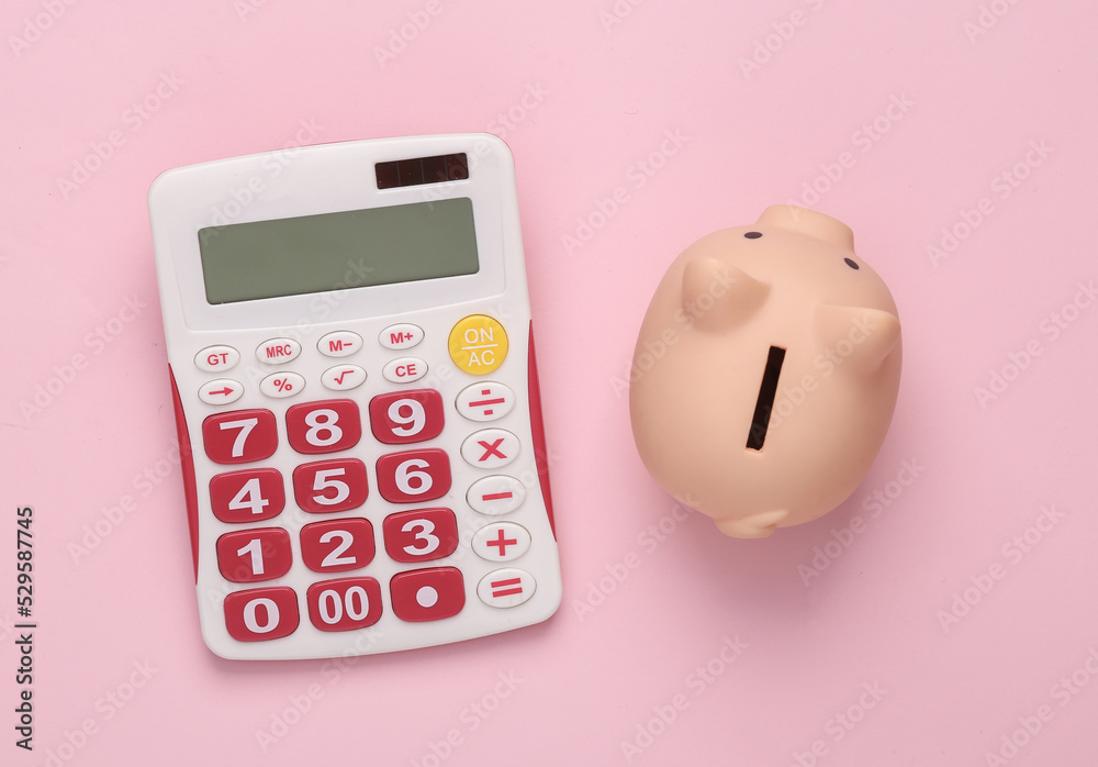 Calculator with piggy bank on pink pastel background. Business concept. Top view Calculator with piggy bank on pink pastel background. Business concept. Top view