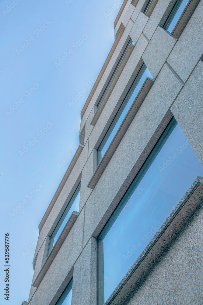 Modern building with windows that reflects blue sky viewed from below Modern building with windows that reflects blue sky viewed from below