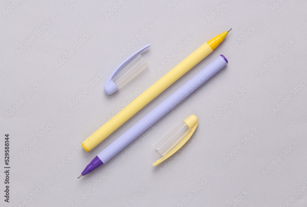 Two pens with caps on a gray background Two pens with caps on a gray background