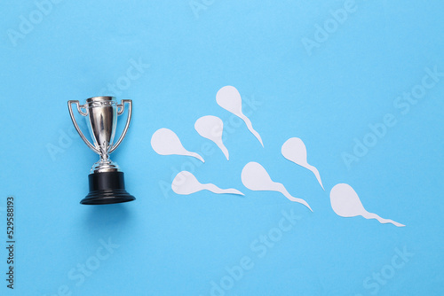 Competing spermatozoa and goblet on a blue background. Conception, ovulation concept photo