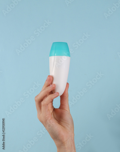 Antiperspirant roll-on stick in female hand on a blue background