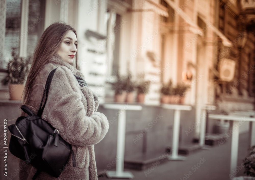 Fashion woman in a luxurious fur coat walking in city Fashion woman in a luxurious fur coat walking in city