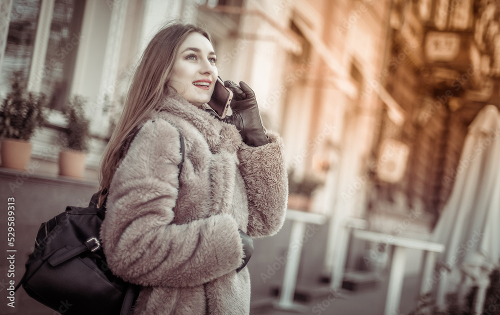 Young attractive fashion blonde woman dressed in fur coat talking on the phone in city Young attractive fashion blonde woman dressed in fur coat talking on the phone in city