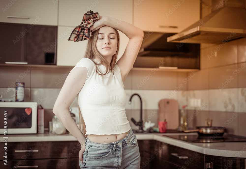 Tired woman cleans up the kitchen, holding rag. House cleaning Tired woman cleans up the kitchen, holding rag. House cleaning