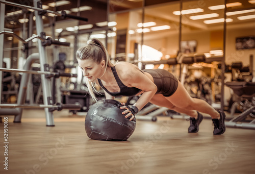 Slim fit Woman push ups with medicine ball in the gym. Functional training