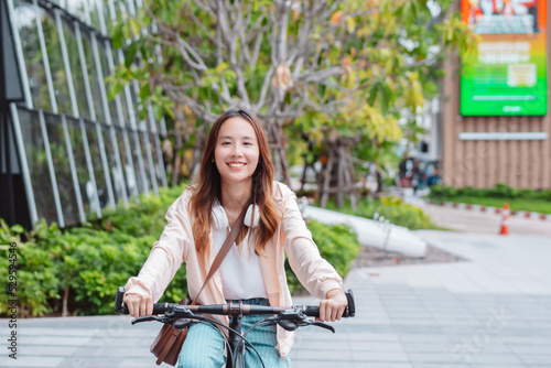 Happy Asian young woman ride bicycle in park, street city in the morning, smiling female using bike of transportation, ECO friendly, People lifestyle concept..