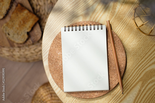 mockup blank sprial notebook top view on wood table with morning sunlight