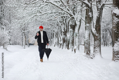 A man on a walk in the park. Young man with in the winter snowfall.