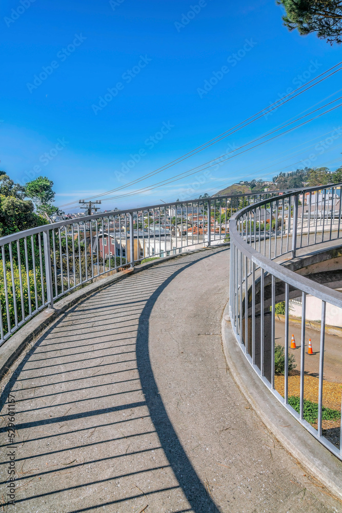 Obraz premium Raised concrete walkway over a road with view of houses in a residential area
