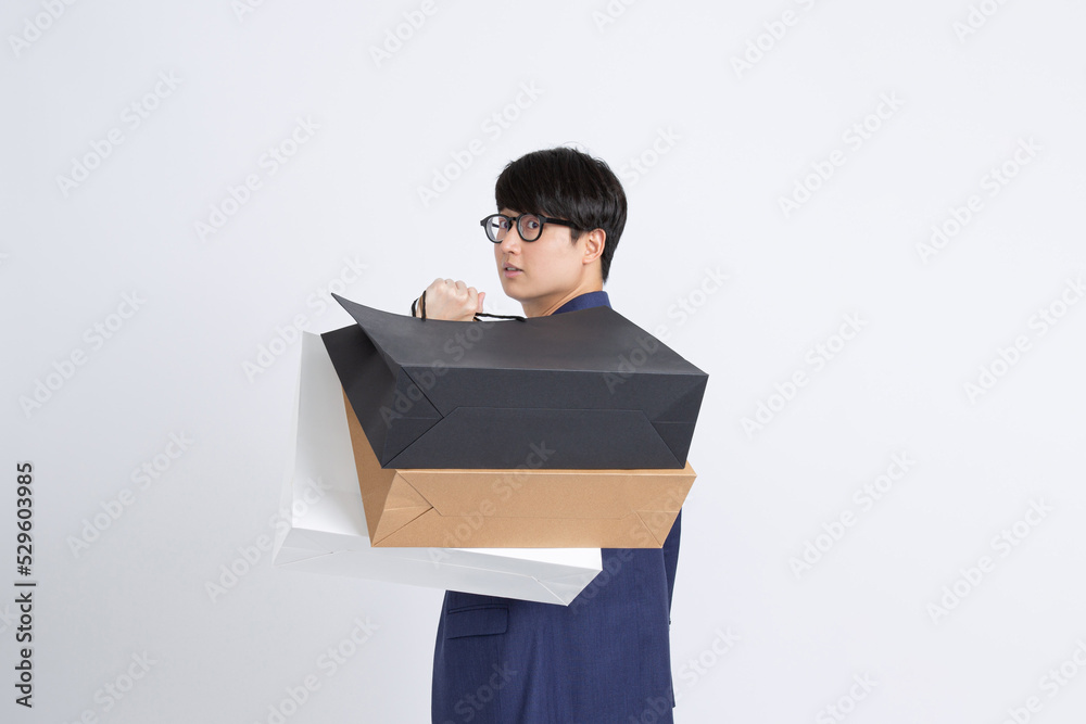 Attractive Asian man holding shopping bag on white background Attractive Asian man holding shopping bag on white background