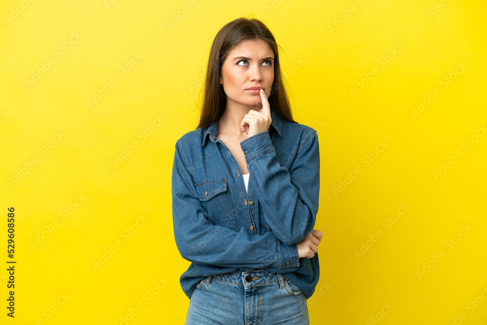 Young caucasian woman isolated on yellow background having doubts while looking up Young caucasian woman isolated on yellow background having doubts while looking up