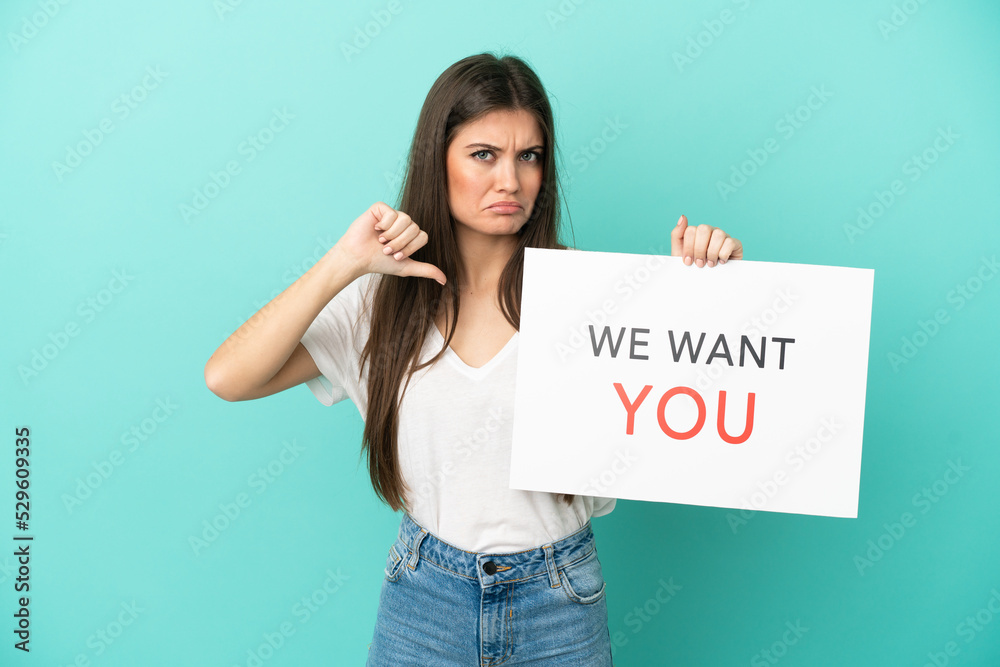 Young caucasian woman isolated on blue background holding We Want You board with proud gesture