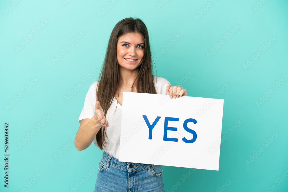 Young caucasian woman isolated on blue background holding a placard with text YES making a deal Young caucasian woman isolated on blue background holding a placard with text YES making a deal