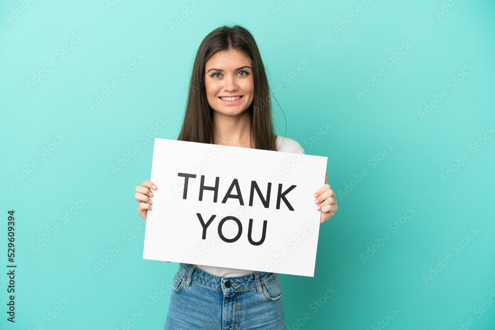 Young caucasian woman isolated on blue background holding a placard with text THANK YOU with happy expression Young caucasian woman isolated on blue background holding a placard with text THANK YOU with happy expression