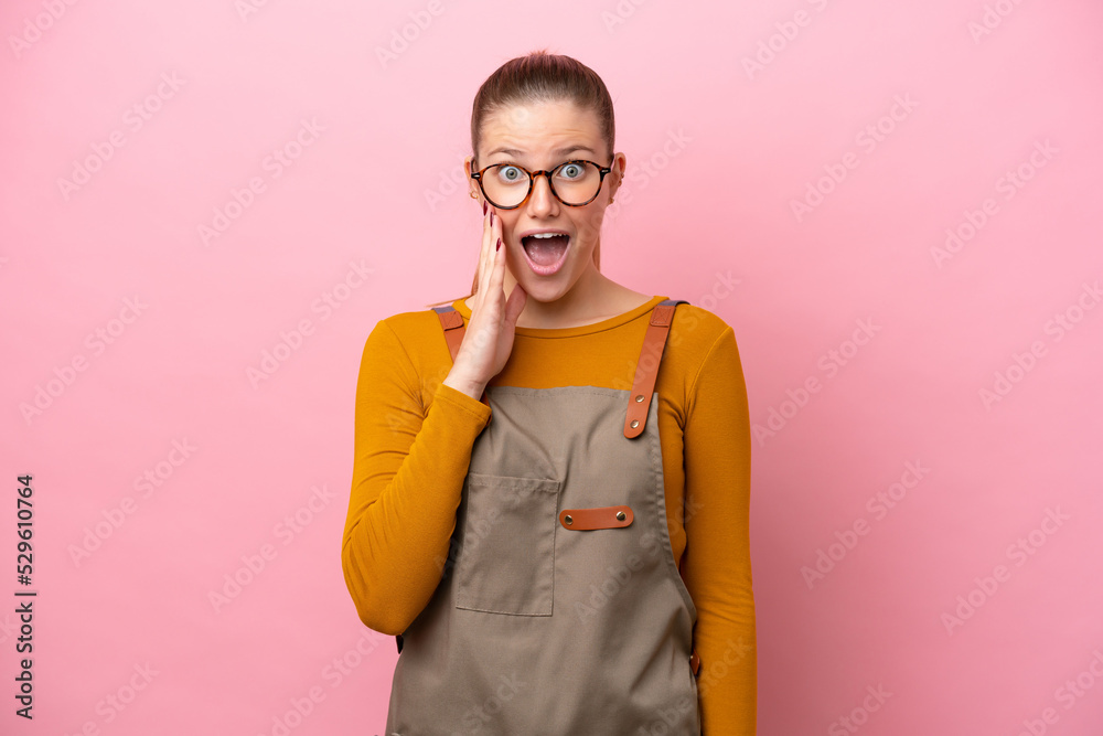 Woman with apron isolated on pink background with surprise and shocked facial expression