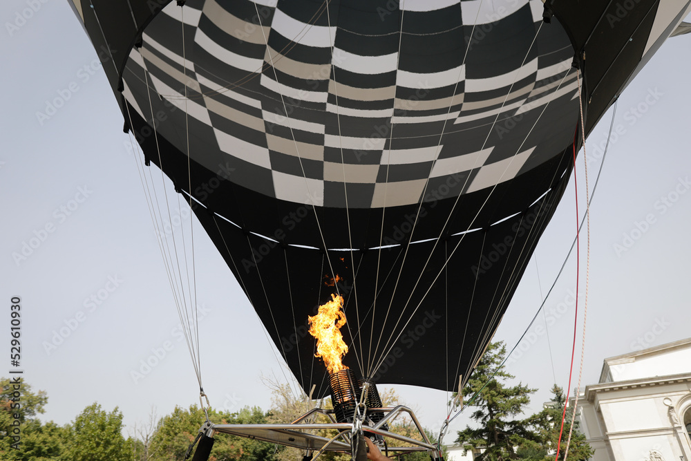 Obraz premium A man uses a double gas burner to inflate a hot air balloon.