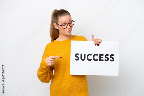 Young caucasian woman isolated on white background holding a placard with text SUCCESS and pointing it