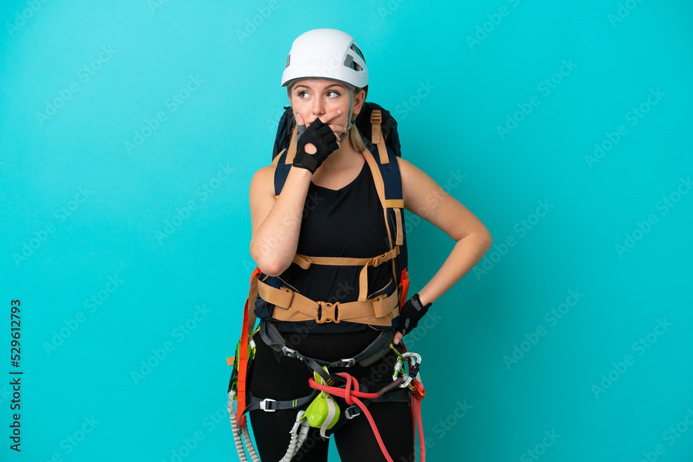 Young caucasian rock climber woman isolated on blue background having doubts and with confuse face expression Young caucasian rock climber woman isolated on blue background having doubts and with confuse face expression