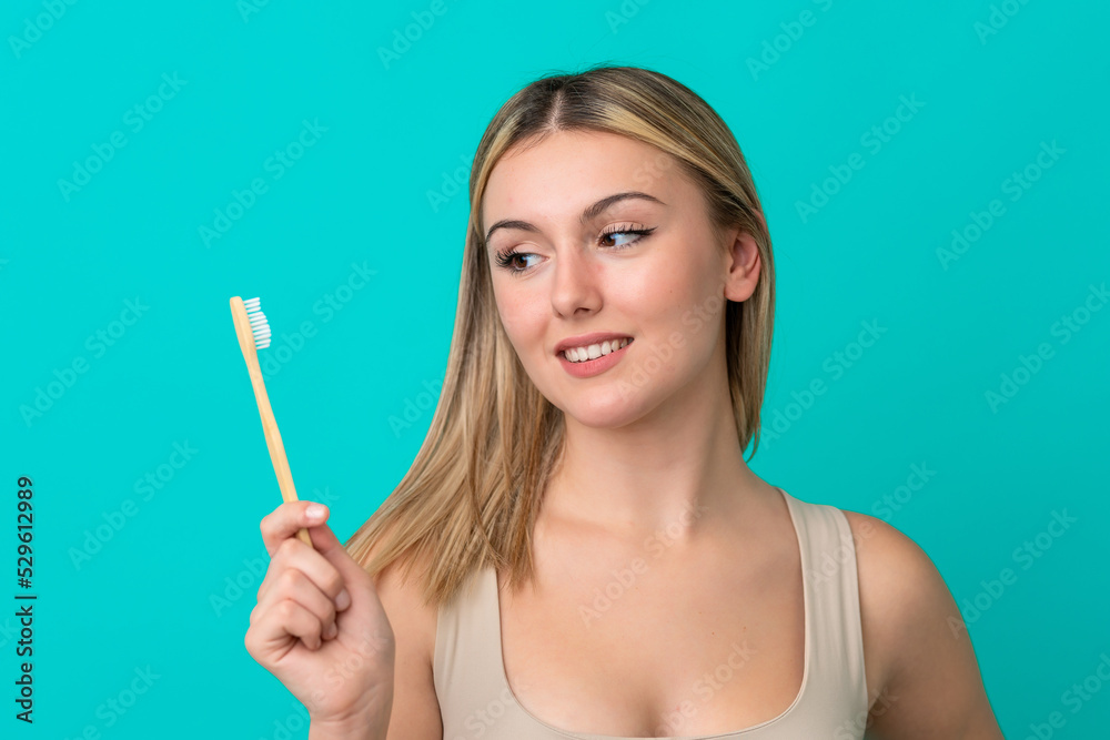 Young caucasian woman isolated on blue background with a toothbrush Young caucasian woman isolated on blue background with a toothbrush