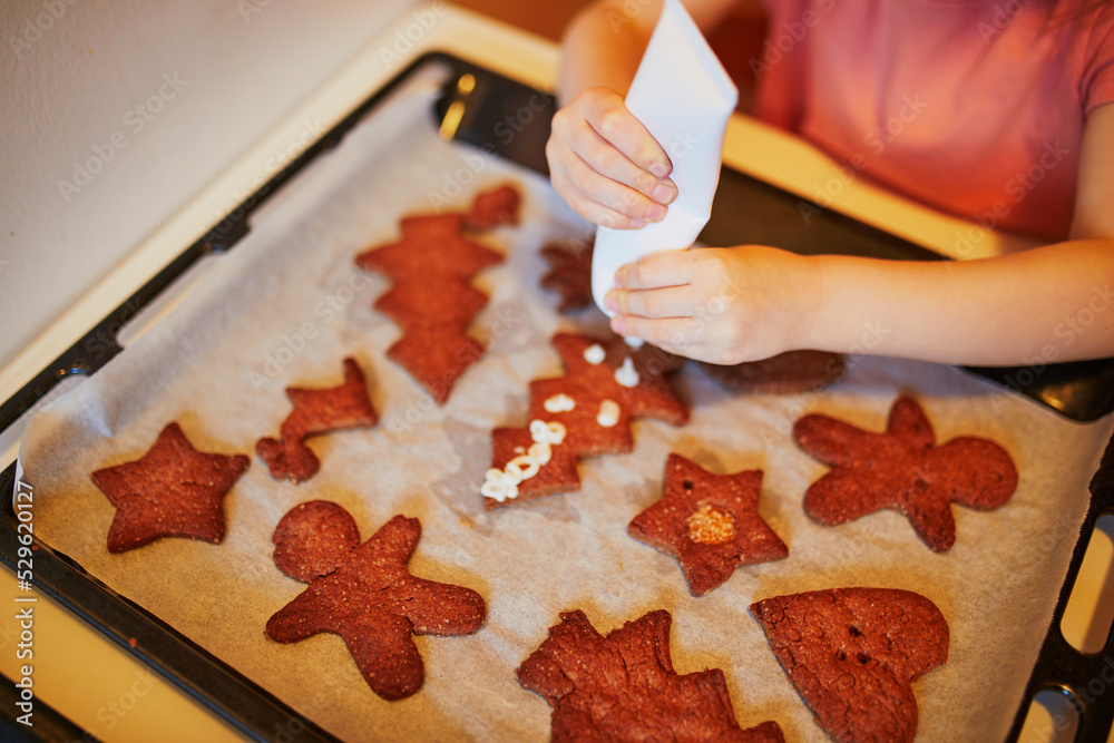Adorable preschooler girl in red Santa hat cooking Christmas cookies Adorable preschooler girl in red Santa hat cooking Christmas cookies