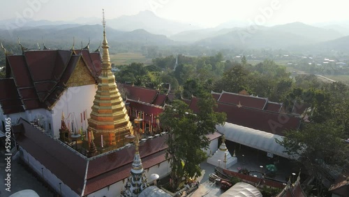 Aerial drone view of beautiful golden pagoda at Wat Phra That Cho Hae Temple in Phrae province, Thailand. Ancient temple in the middle the jungle, Travel destination photo