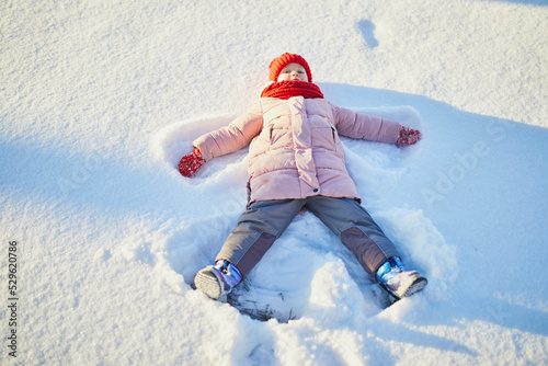 Adorable preschooler girl having fun in beautiful winter park on a snowy cold winter day