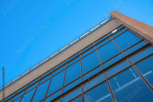 Modern commercial building lined with glass windows against clear blue sky