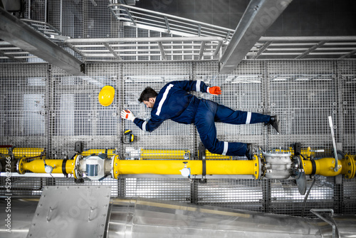Accident at oil production refinery plant and injured worker lying down unconscious on metal platform.