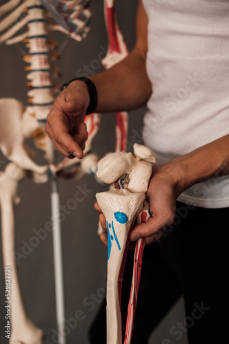 A man holds a skeleton leg in his hands and points a finger at it