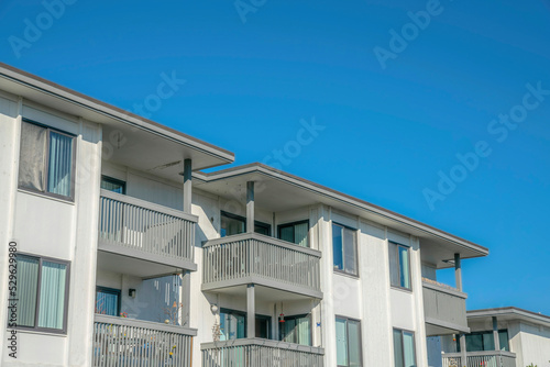 Homes with balconies and white walls against blue sky in Del Mar California © Jason