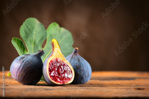 Fig fruit close up. Ripe fig fruits with leaf close-up. Beautiful sweet fresh organic figs on a wooden table. Label design. Healthy vegan food. 