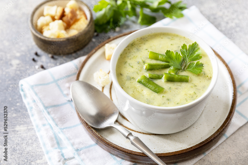 Healthy food. Vegan soup puree of green vegetables. Bowl of green bean and zucchini cream soup on a stone table. Healthy food. Vegan soup puree of green vegetables. Bowl of green bean and zucchini cream soup on a stone table.