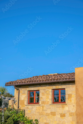 Home exterior with stone wall against blue sky at Del Mar Southern California © Jason