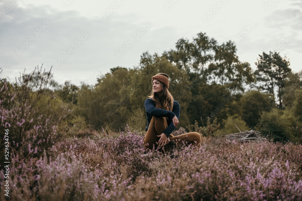 Fototapeta premium woman sat outdoors looking peaceful, with muted autumnal tones