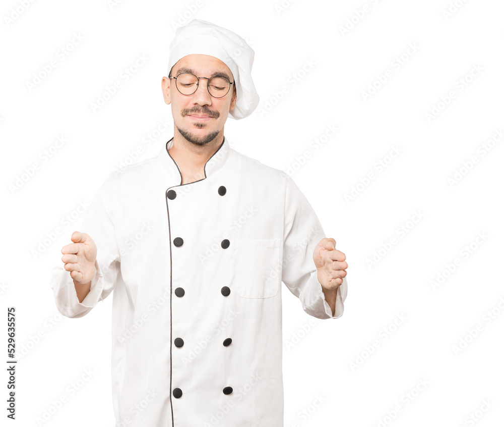 Confident young chef doing a gesture of holding something with his hands Confident young chef doing a gesture of holding something with his hands