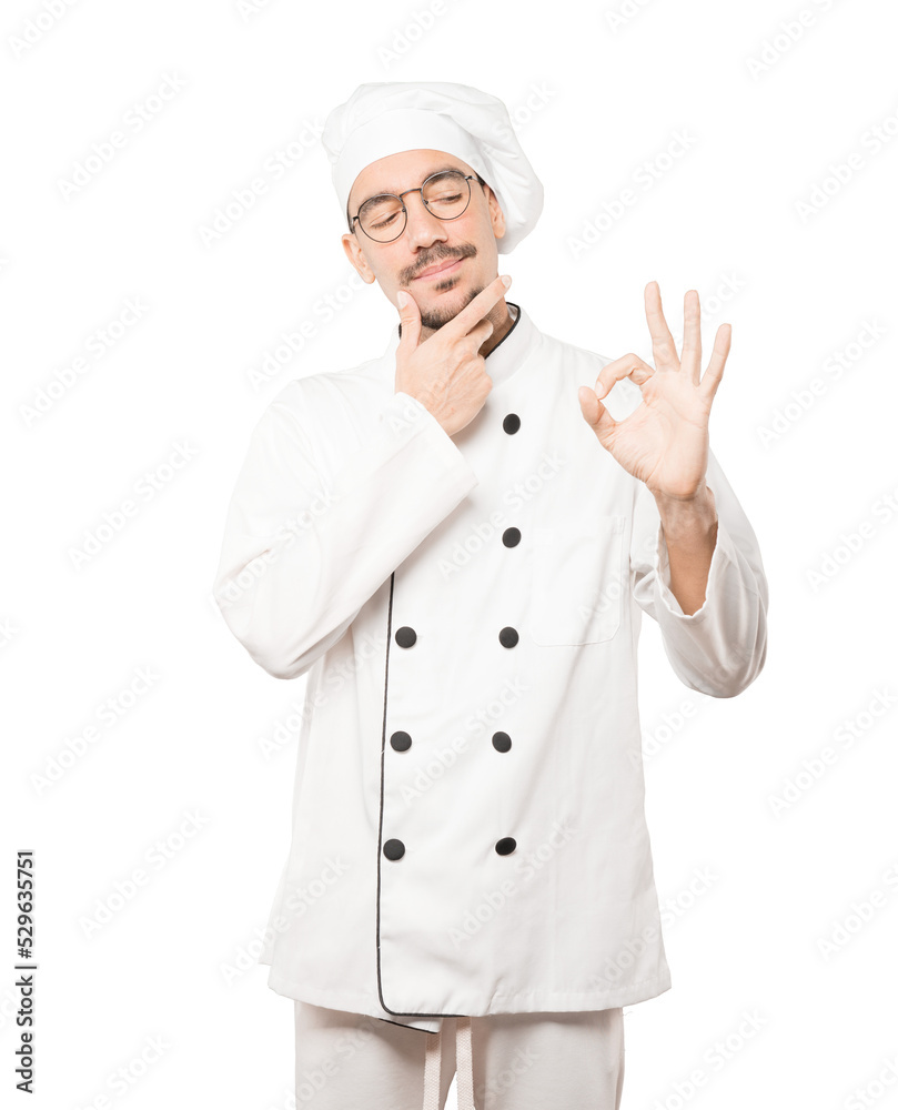 Worried young chef doubting and making a gesture of approval Worried young chef doubting and making a gesture of approval