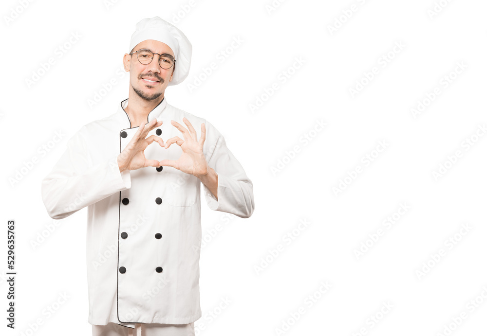 Happy young chef doing a gesture of love with his hands Happy young chef doing a gesture of love with his hands