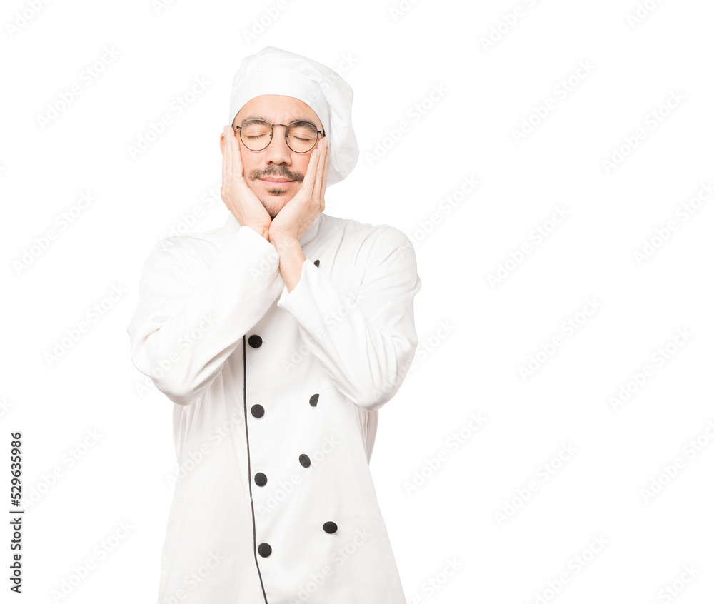 Relaxed young chef making a gesture of sleep Relaxed young chef making a gesture of sleep