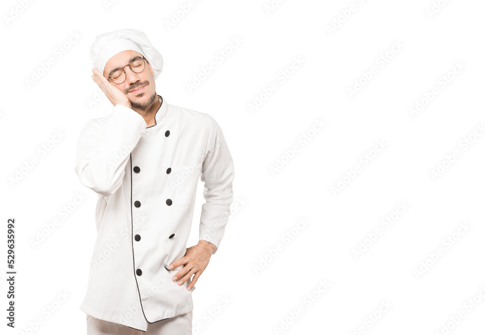 Relaxed young chef making a gesture of sleep Relaxed young chef making a gesture of sleep