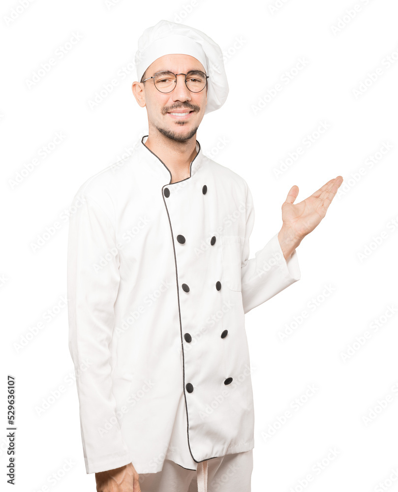 Friendly young chef making a gesture of welcome Friendly young chef making a gesture of welcome