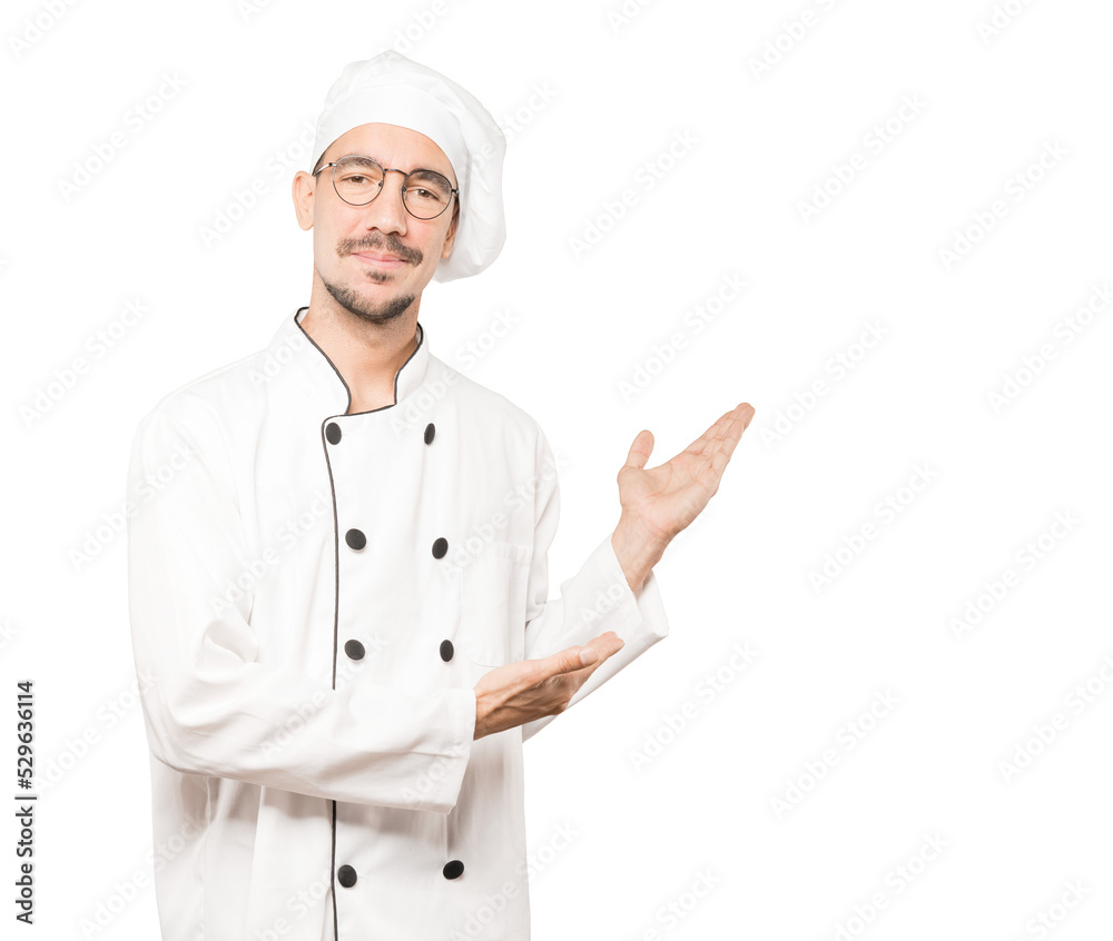 Friendly young chef making a gesture of welcome Friendly young chef making a gesture of welcome