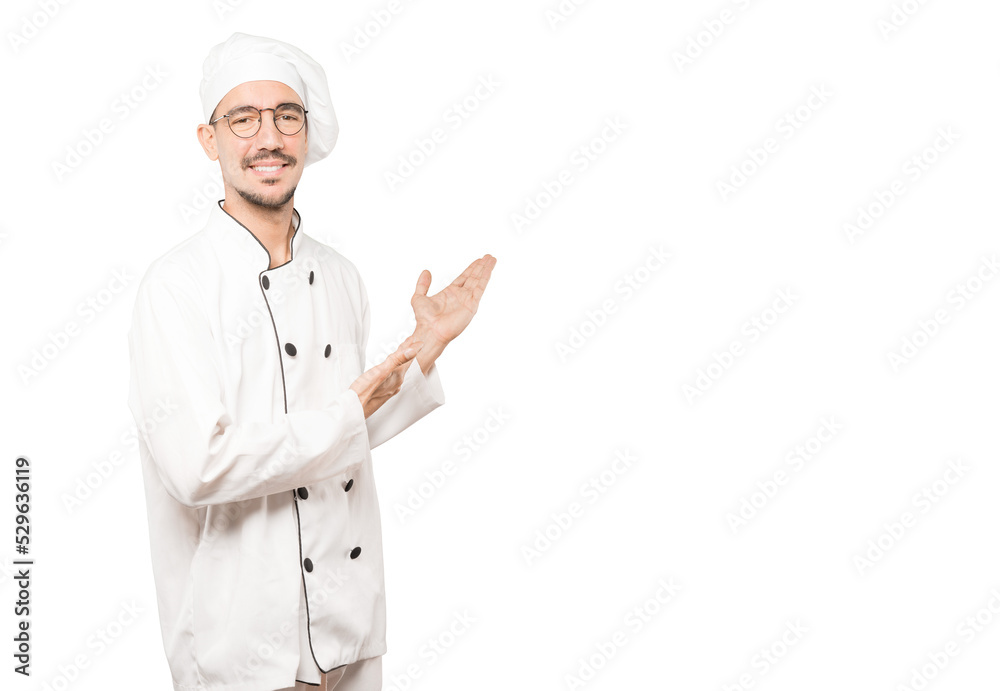Friendly young chef making a gesture of welcome Friendly young chef making a gesture of welcome