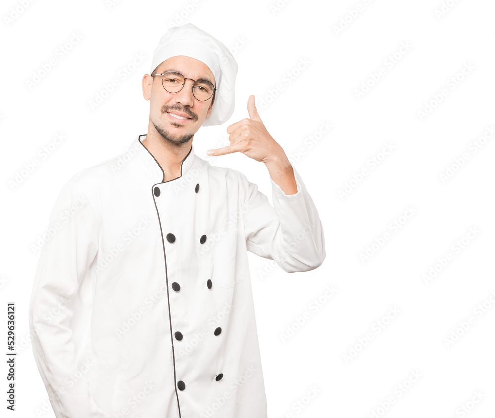 Happy young chef making a gesture of calling with the hand Happy young chef making a gesture of calling with the hand